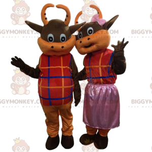 2 brown and orange cows dressed in colorful outfits -