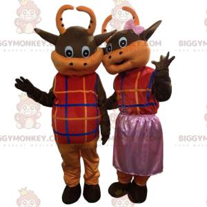 2 bruine en oranje koeien gekleed in kleurrijke outfits -