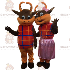 2 brown and orange cows dressed in colorful outfits -